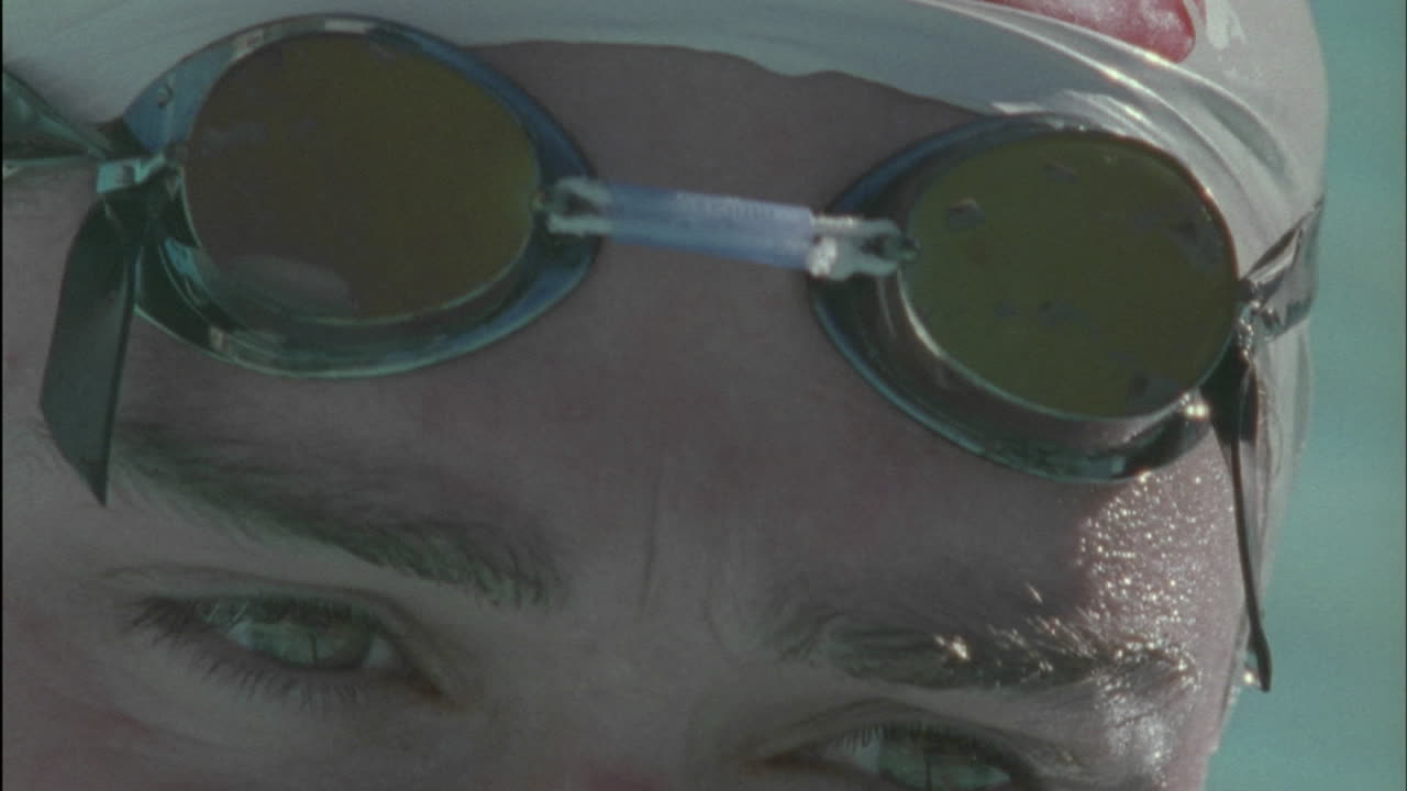 수영하는 사람이 수영을 준비하기 위해 고글을 착용합니다.