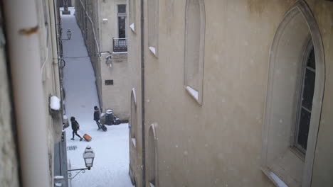 people walking in snowy streets with their suitcases view from a high window.