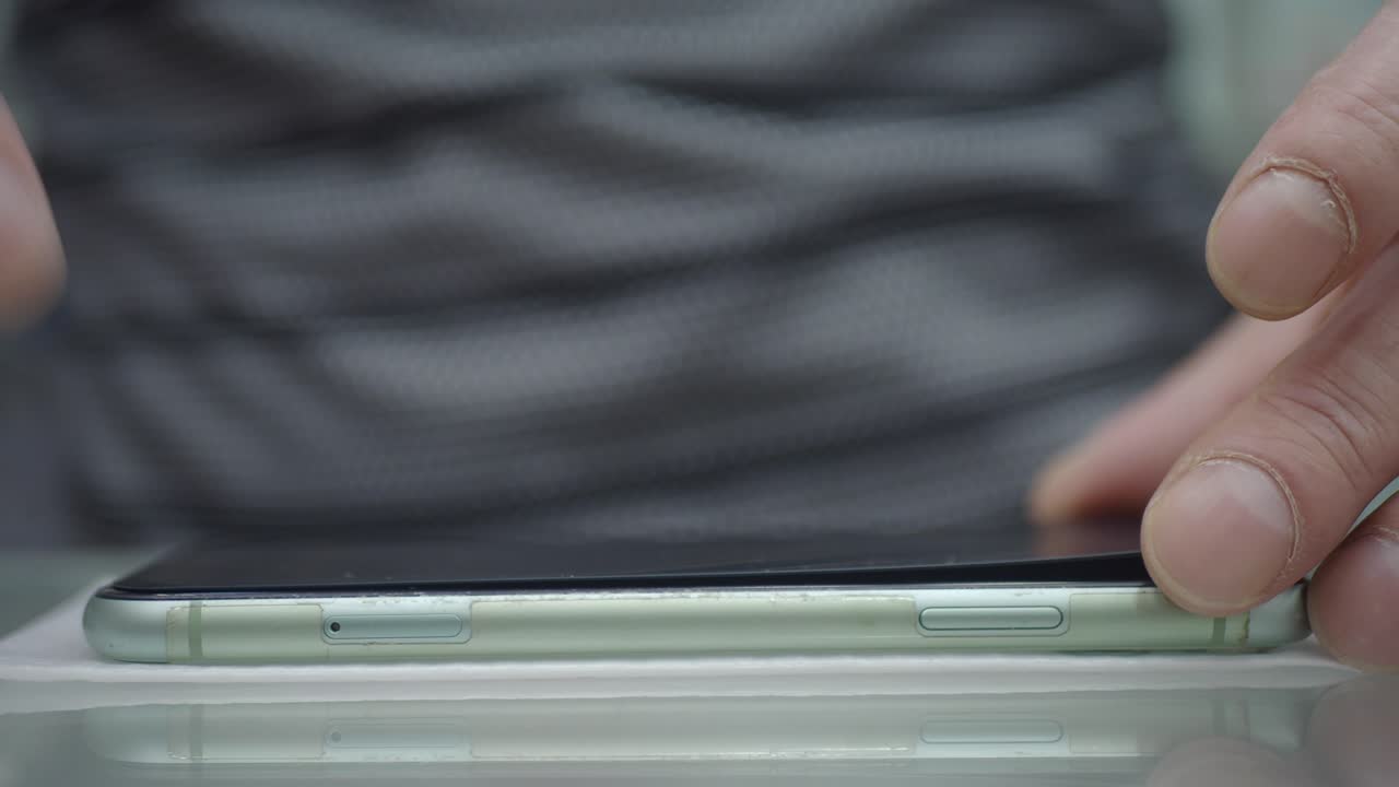 사람이 스마트폰에 스크린 보호기를 적용합니다.