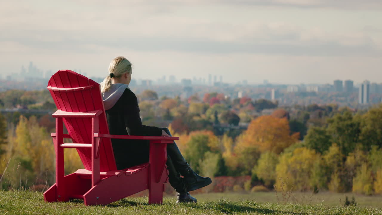 Woman Relaxing in a Red Chair Overlooking City Skyline