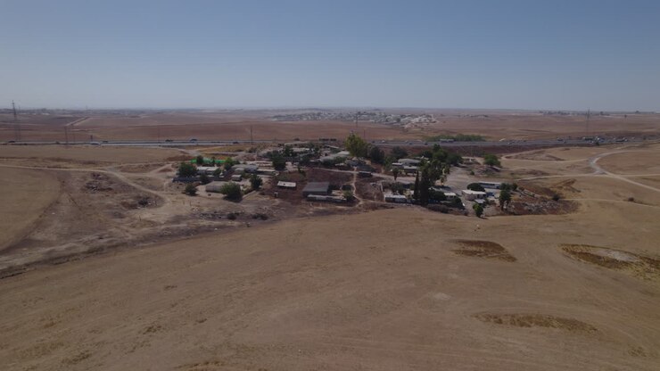 Fotografia parallasse di case senza permesso in un'area remota e desertica, vicino a un'autostrada, con terreno arido e senza colture-1