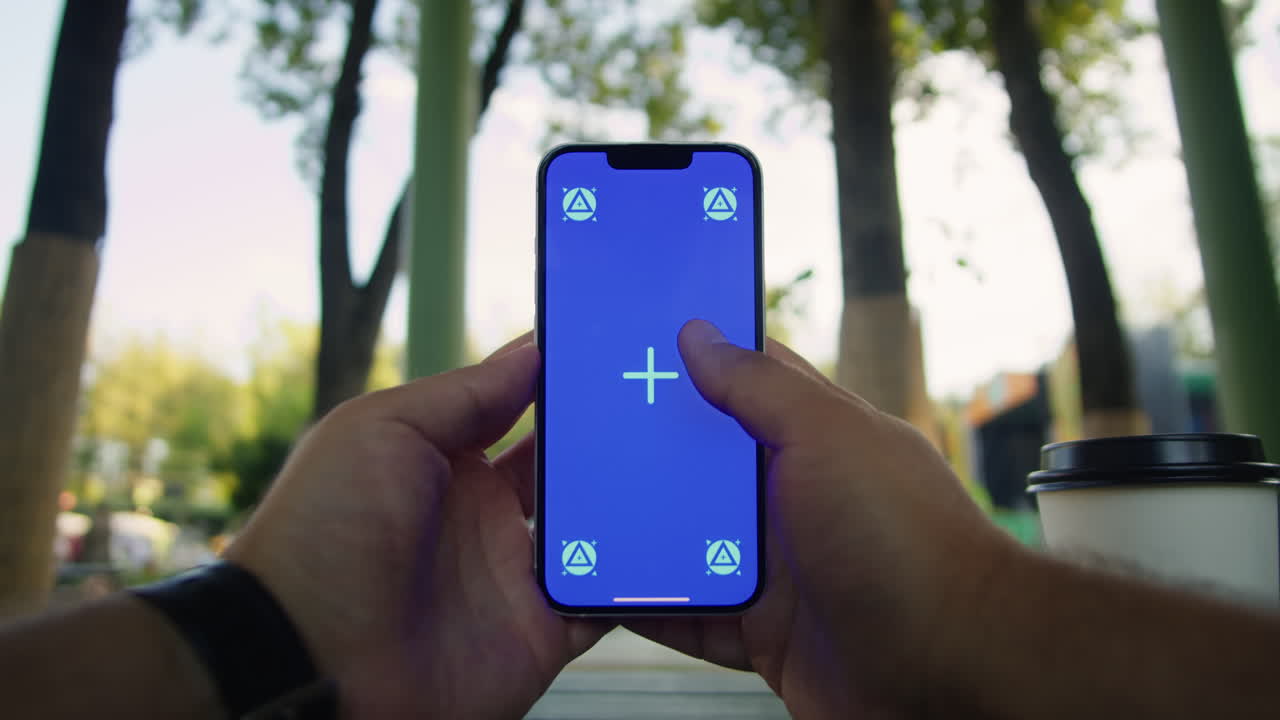 Young woman holding and swiping phone chroma key screen in the park in front of trees close-up. Girl with green screen on smart phone. Nature