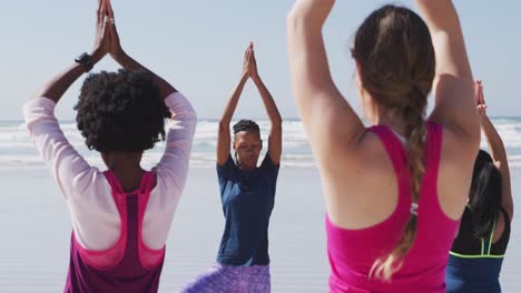 Multiethnische-Gruppe-Von-Frauen,-Die-Yoga-Position-Am-Strand-Und-Im-Hintergrund-Des-Blauen-Himmels-Machen