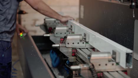 man placing an aluminum bar in an automatic drilling machine