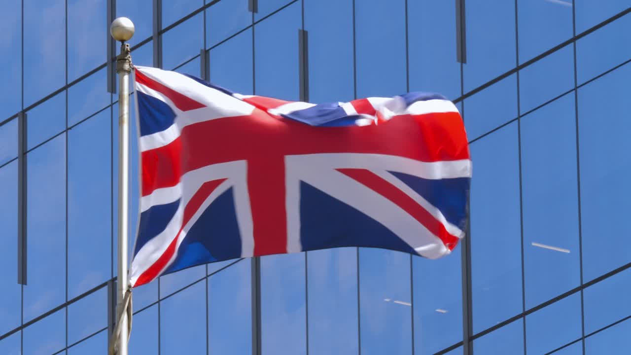 la bandera británica ondeando frente a las ventanas de vidrio del edificio.