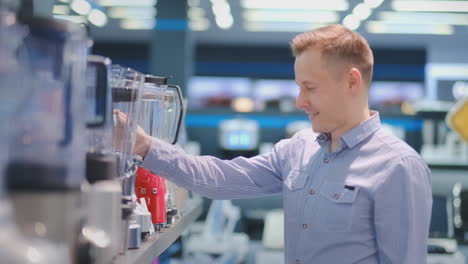 young handsome man in appliances store chooses blender for his cuisine