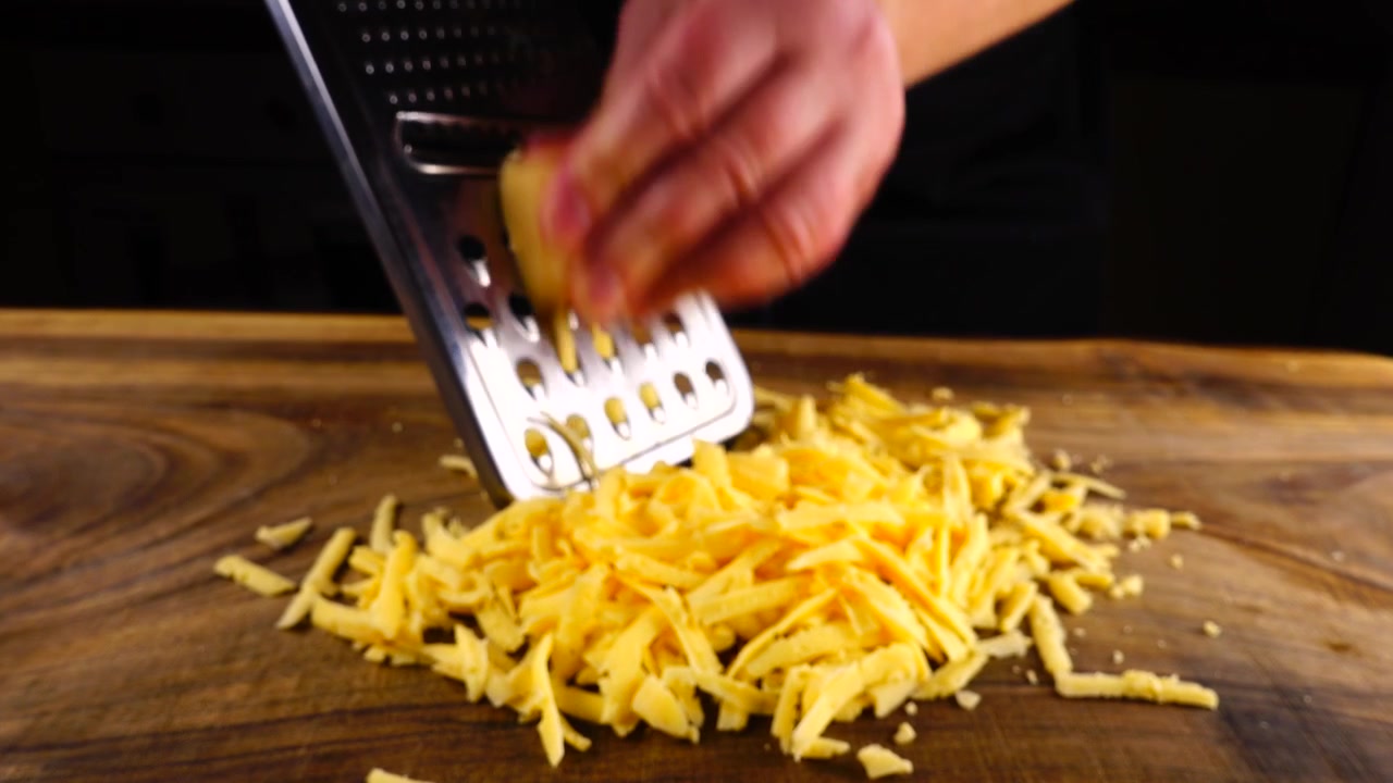 Lo chef strofina formaggio grattugiato su un tagliere
