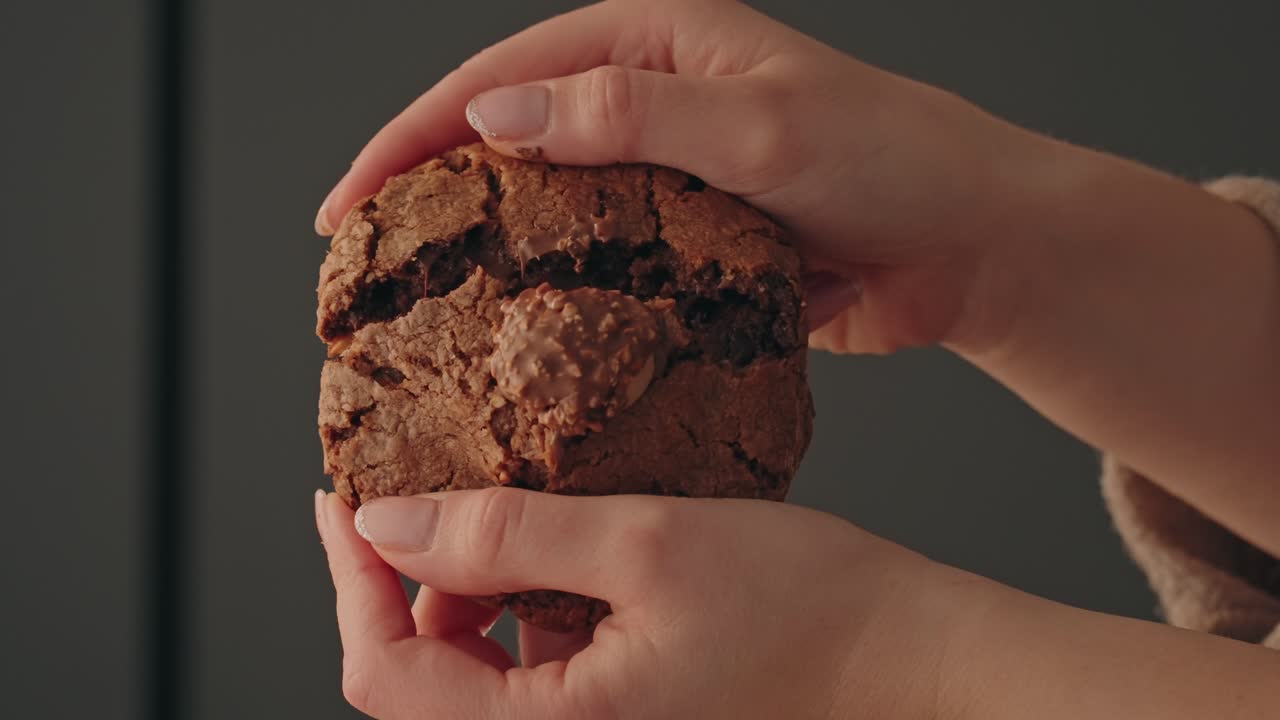 Close up hands splitting baked chocolate cookie indoors