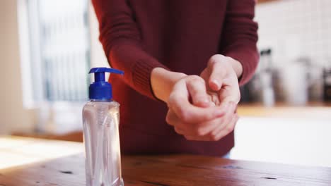 Mid-section-of-woman-sanitizing-her-hands-at-home