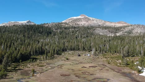 drone fly's over alpine meadow with cabins and a meandering stream