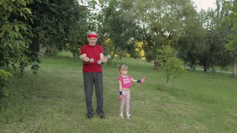 nieta y abuelo haciendo ejercicios de fitness con pesas. hombre mayor con niño niña
