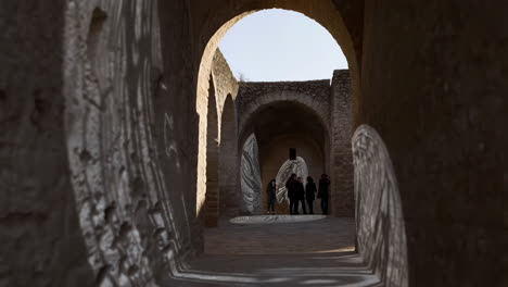 People viewing a light art installation within historic stone arches