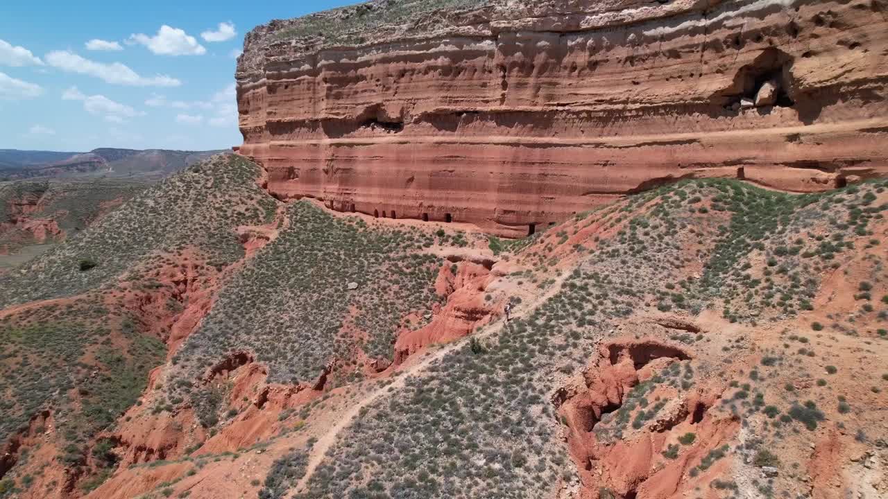 excursionista subiendo a una montaña roja mística en un desierto de cañón rojo en teruel, españa
