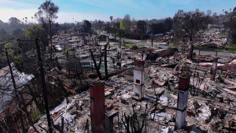 aerial view of a residential neighborhood devastated by a wildfire, showing widespread destruction, burned homes, and charred landscape