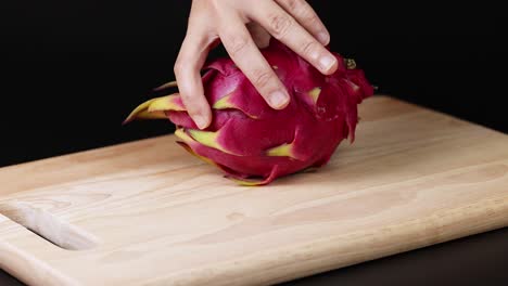 las manos manipulan la fruta del dragón en la tabla de madera