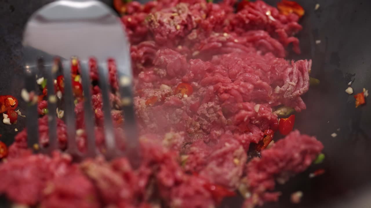 Close-up of beef stir fry cooking in a pan with vibrant ingredients and steam