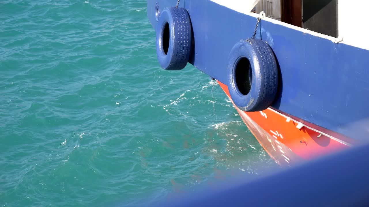 Blue-painted car tires, attached as bumpers on the ferry's side