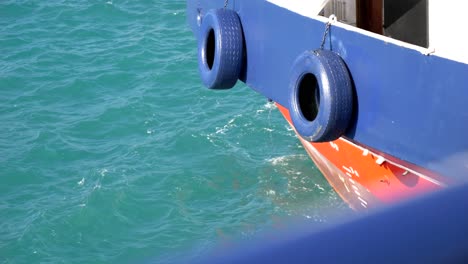 blue-painted car tires, attached as bumpers on the ferry's side