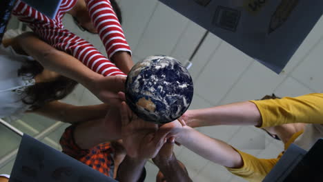 animation of rotating globe over group of diverse business team holding hands