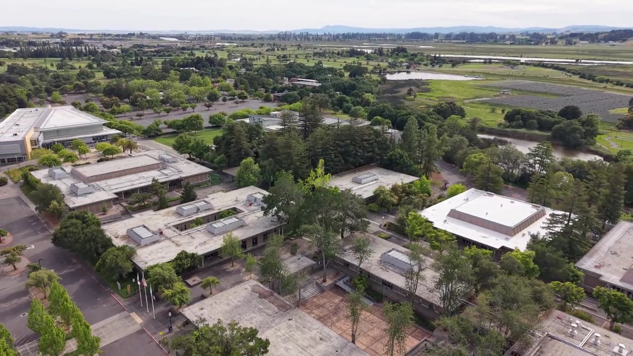 Vista aérea do campus do Napa Valley College em Napa, Califórnia, mostrando seus edifícios acadêmicos, pátios, estacionamentos e a paisagem verdejante circundante com um rio próximo