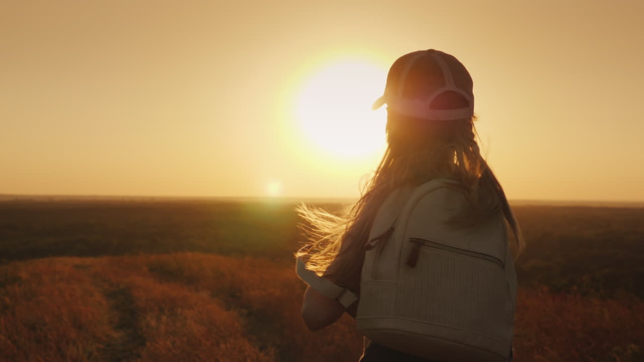 un niño de pelo largo con una mochila corre hacia el sol, los sueños de los niños y el concepto de vacaciones