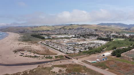 wide aerial shot flying over morro strand state beach towards the town of morro bay, california. 4k