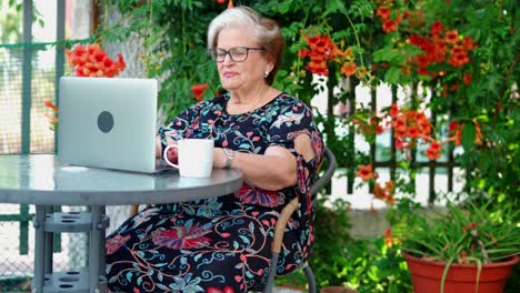 Aged-female-using-laptop-at-table-near-plants