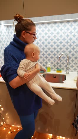 madre sosteniendo al bebé en una cocina