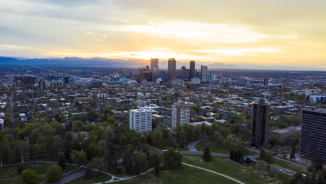 aerial time lapse over denver's cheesman park and surrounding residential area with the sun setting in the background