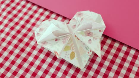 decorative origami paper heart on red and white checkered tablecloth