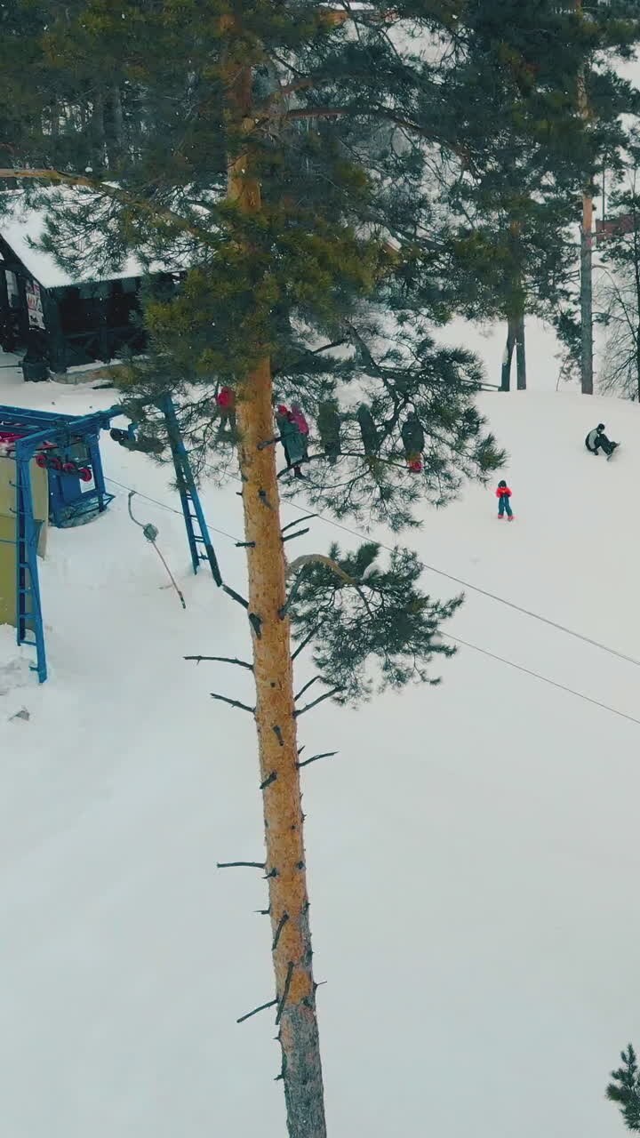 modern ski resort with operating t-bar lift and resting people on mountain top on nasty winter day upper view