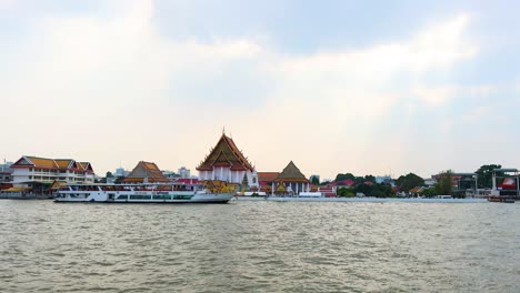 a boat travels past a riverside temple