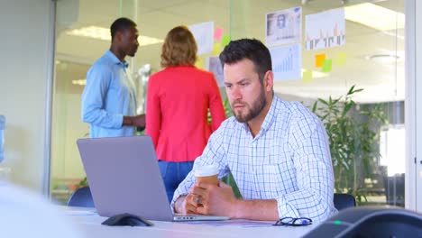 Front-view-of-young-caucasian-businessman-working-on-laptop-in-modern-office-4k