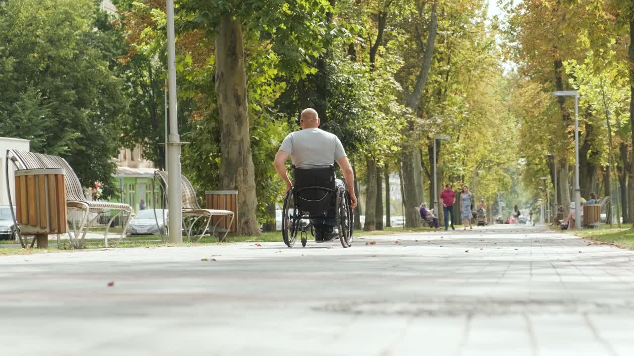 체어 에 앉아 있는 장애인 남자 가 공원 골목 에서 산책 하고 있다
