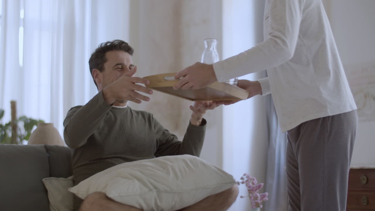 예쁜 게이가 아침에 침대에서 그의 연인에게 아침 식사를 가져오고