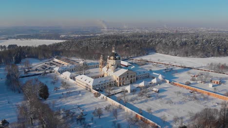 Aerial-view-of-the-Pazaislis-monastery-and-the-Church-of-the-Visitation-in-Kaunas,-Lithuania-in-winter,-snowy-landscape,-Italian-Baroque-architecture,-flying-away-from-the-monastery,-zoom-out