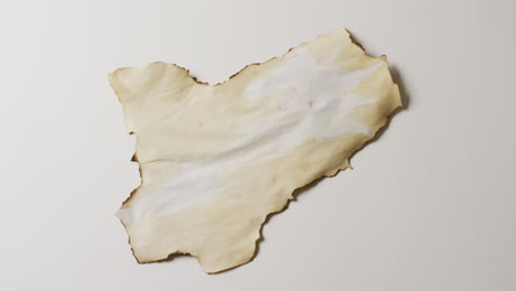 video de un primer plano de un pedazo de papel con bordes quemados sobre un fondo blanco