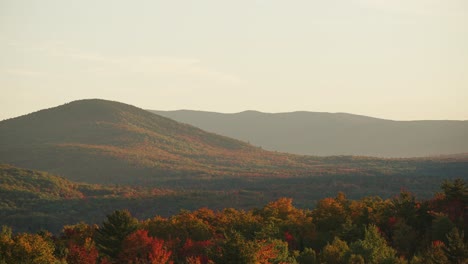 pan across sweeping view of vibrant red orange rolling hills during peak fall, white mountains nh