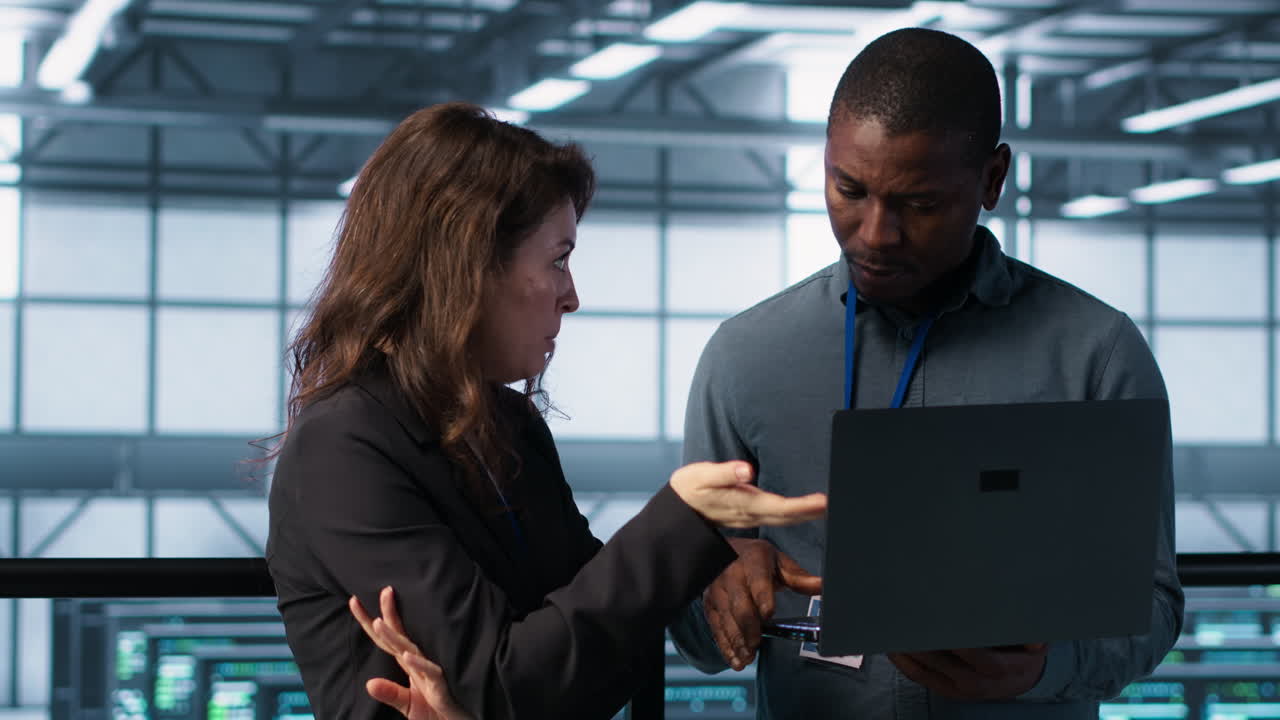 Developers in data center workspace coding on laptop, analyzing metrics