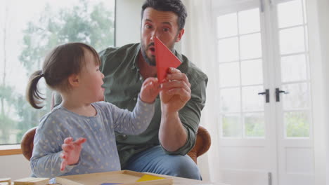 Padre-Con-Hija-Con-Síndrome-De-Down-Jugando-Con-Formas-De-Madera-En-Casa-Juntos