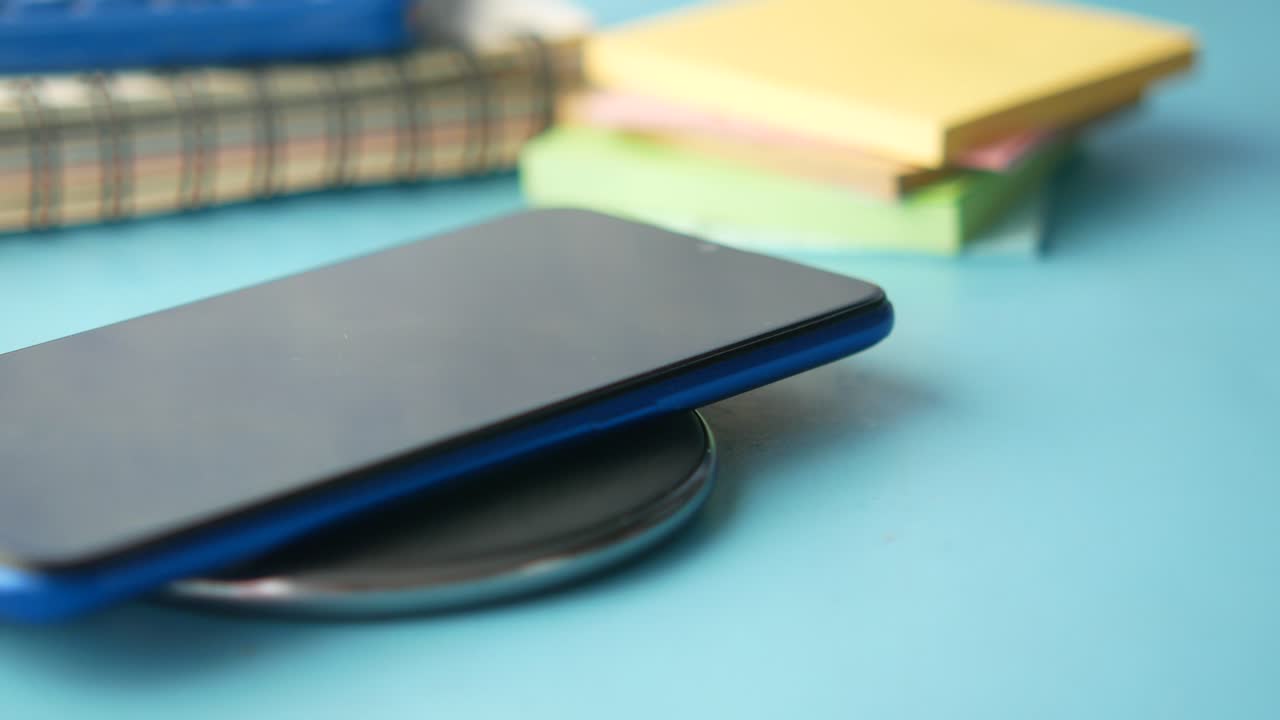 teléfono inteligente de carga inalámbrica en un escritorio con materiales de estudio