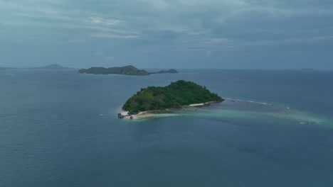 Flying-around-a-small-tropical-island,-surrounded-by-other-islands-shrouded-in-mist