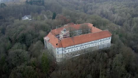 Vista-Aérea-De-Drones-Del-Tradicional-Pueblo-Alemán-Herzberg-Am-Harz-En-El-Famoso-Parque-Nacional-En-Alemania-Central-En-Un-Día-Nublado-En-Invierno.