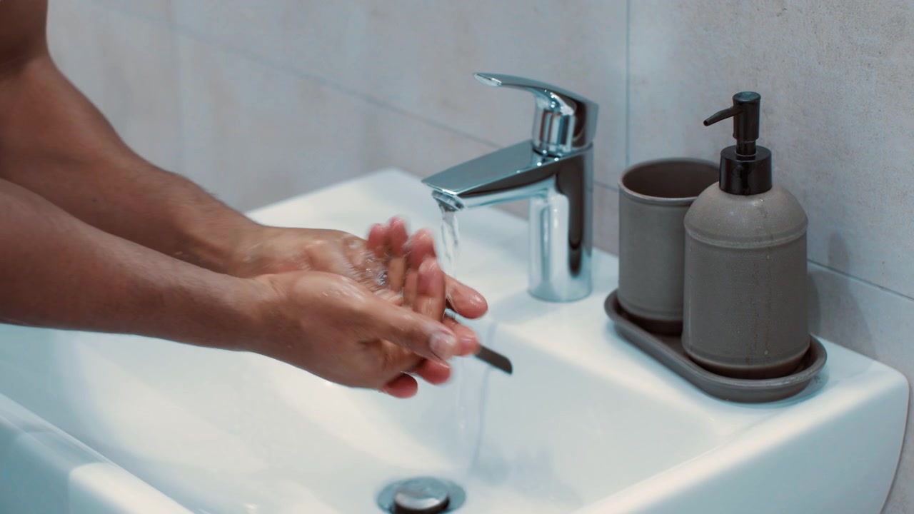 Persona che si lava le mani con il sapone in un lavandino moderno del bagno
