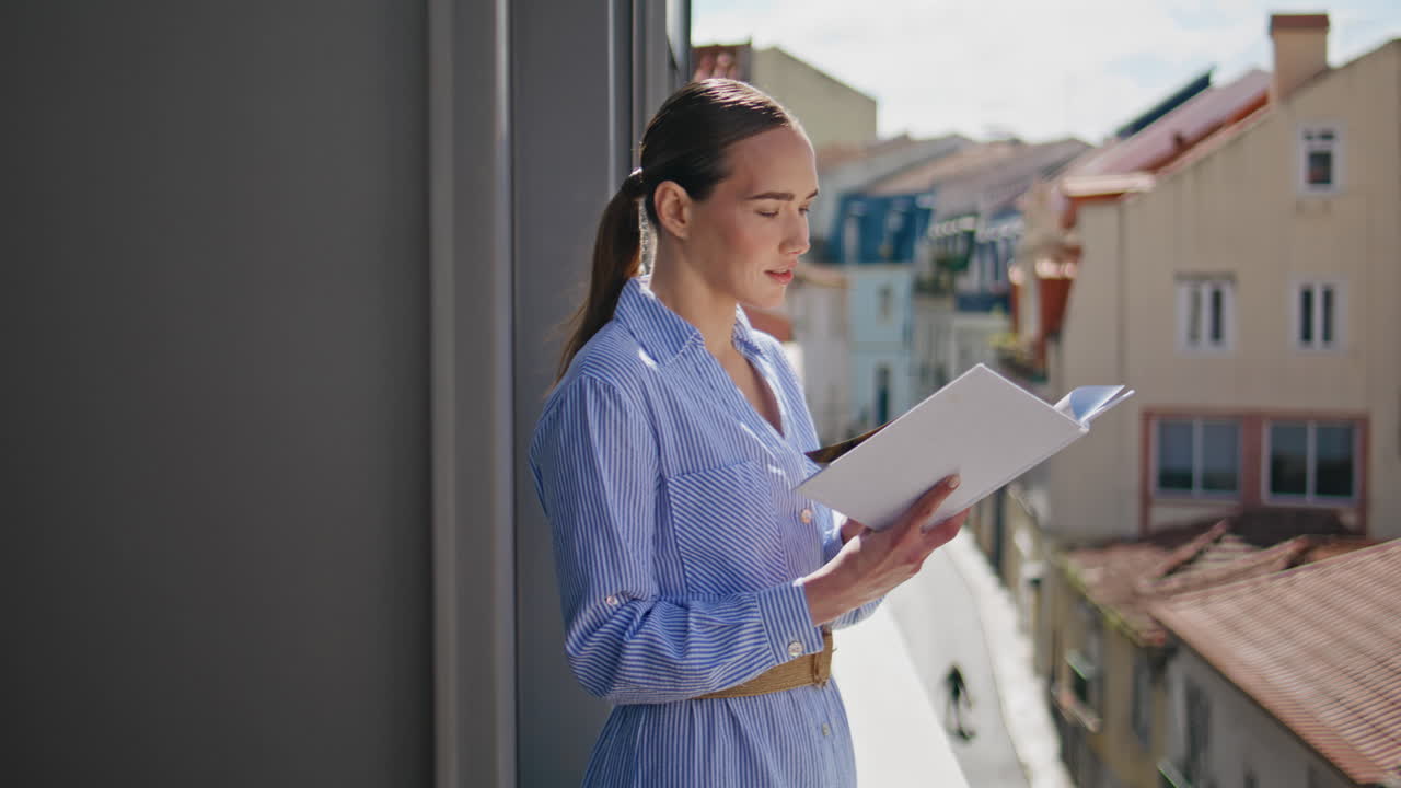 Relaxed model reading book at cityscape balcony closeup. Lady flipping pages