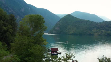 Toma-Aérea-Revelada-Rodando-A-Través-De-Un-Bosque-Para-Mostrar-El-Lago-Perucac-En-Serbia