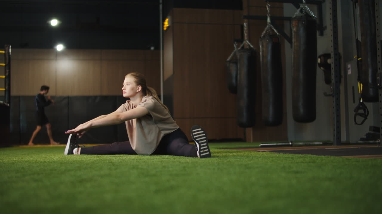 mujer de fitness ambiciosa haciendo splits en el gimnasio. chica en forma calentándose en el club deportivo