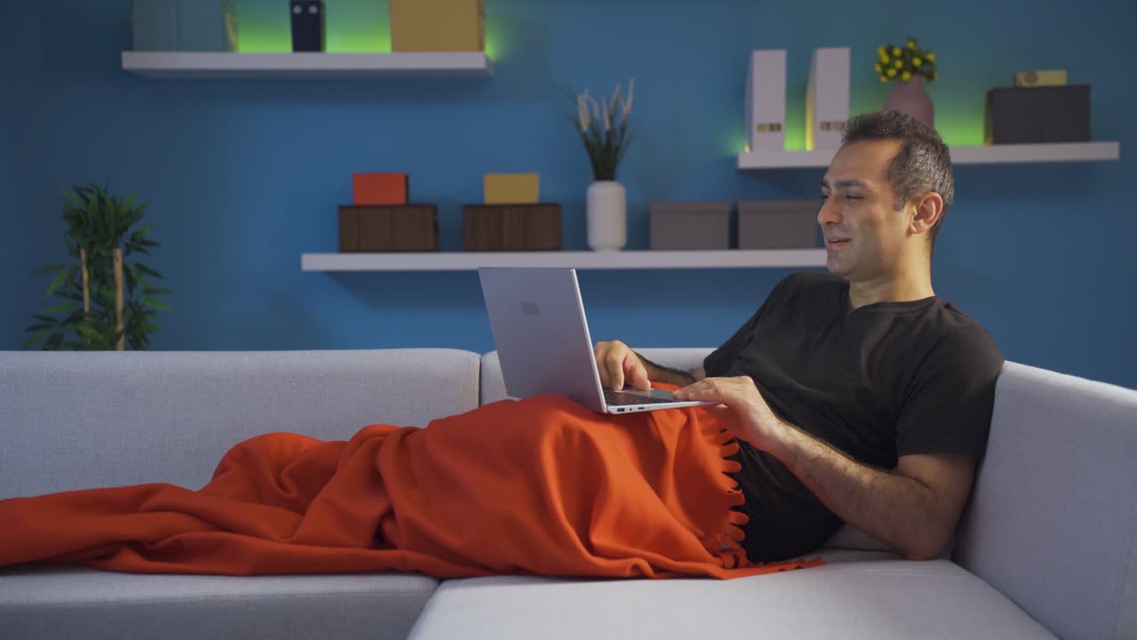 hombre acostado hablando por facetime en su computadora portátil.