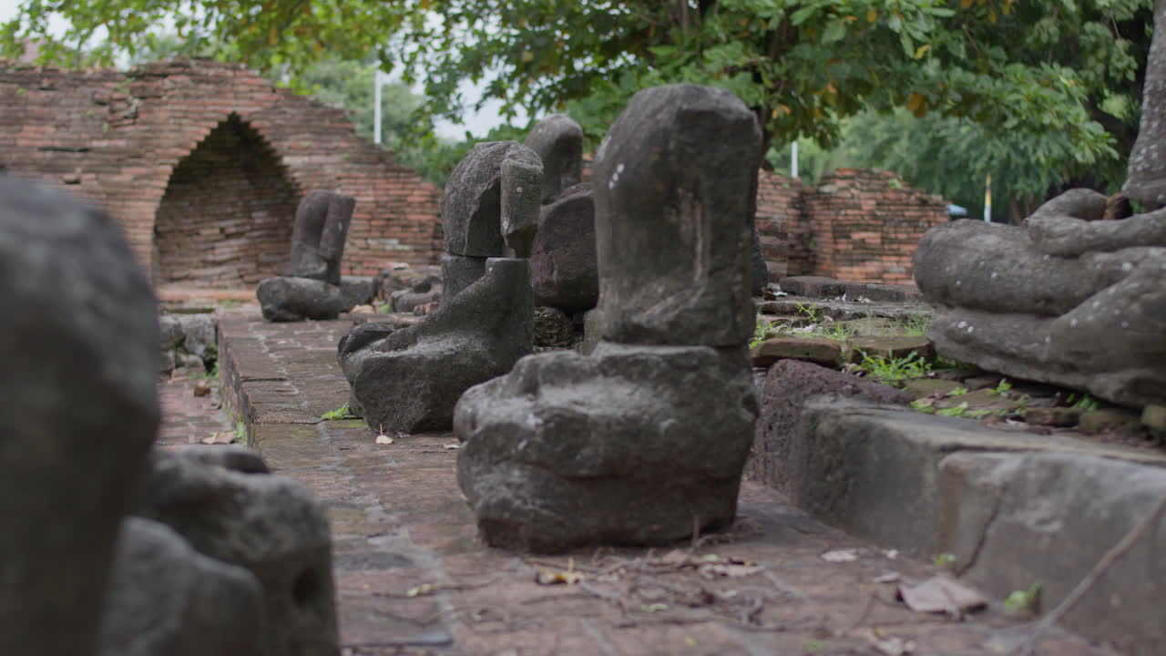 Buddha field of broken sculpture with beautiful ancient Buddha statue in middle of green nature, collection of old Buddha heads and busts covered with moss in Wat Umong temple in Chiang Mai, Thailand