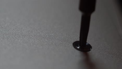 macro view of screw being removed from a notebook